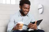 business, people and technology concept - african american businessman with tablet pc computer drinking coffee at office stairs