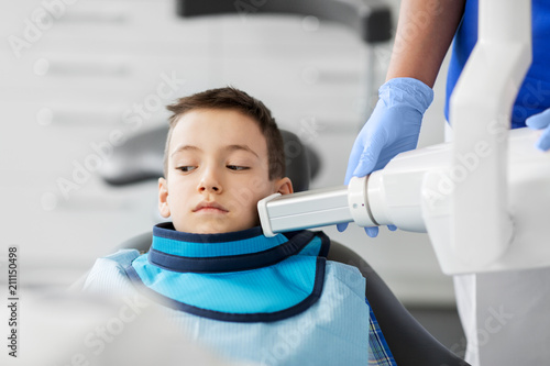 medicine, dentistry and healthcare concept - female dentist with x-ray machine scanning kid patient teeth at dental clinic