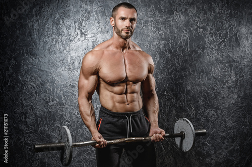 Fotografie Muscular bodybuilder exercising with a barbell
