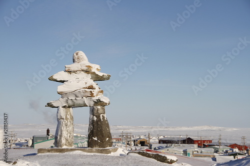 Inukshuk or Inuksuk landmark covered in snow found on a hill in the community of Rankin Inlet, Nunavut in February