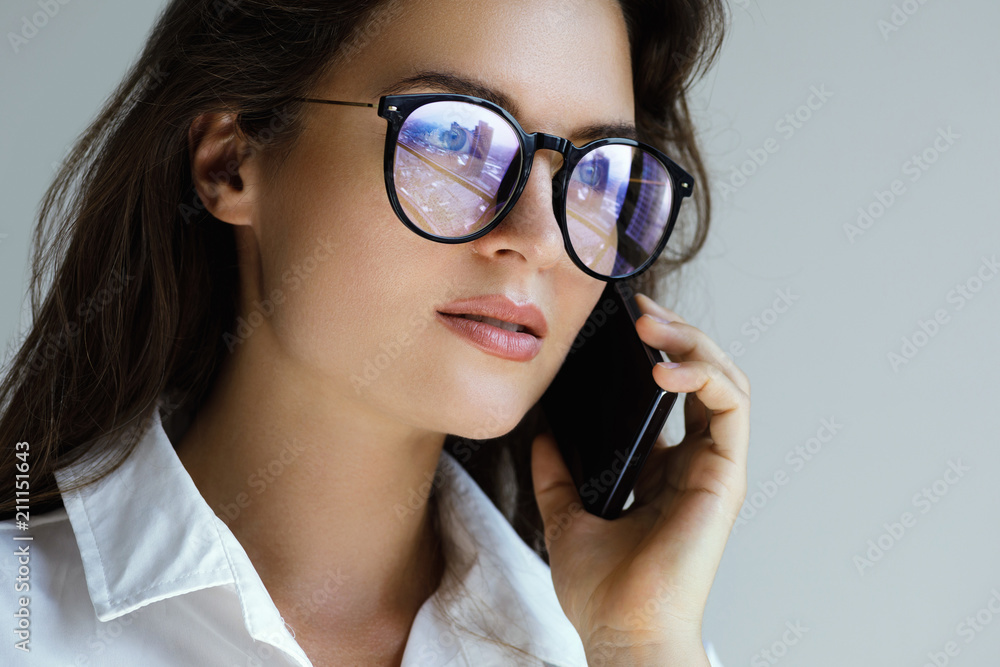Young businesswoman in eyeglasses talking by smartphone Young businesswoman in eyeglasses talking by smartphone