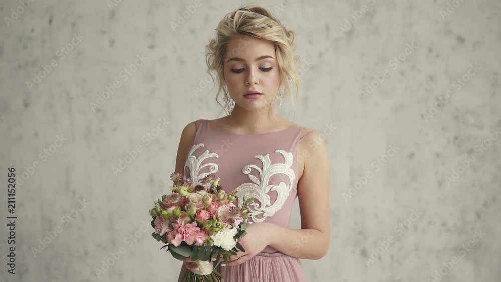 Portrait of an attractive girl with a bouquet of flowers in her hands. charming blonde in evening dress Portrait of an attractive girl with a bouquet of flowers in her hands. charming blonde in evening dress