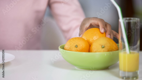 Fototapeta Naklejka Na Ścianę i Meble -  Female hand taking organic orange from plate, body care, fresh juice on table