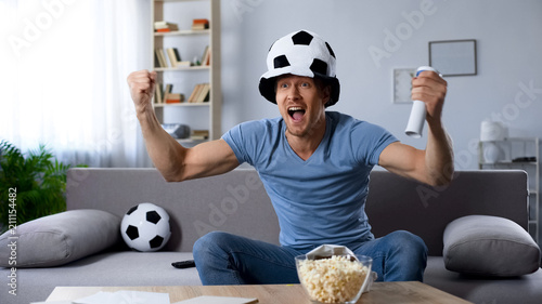 Football supporter in fan hat sincerely rejoicing to scored kick at last minutes photo