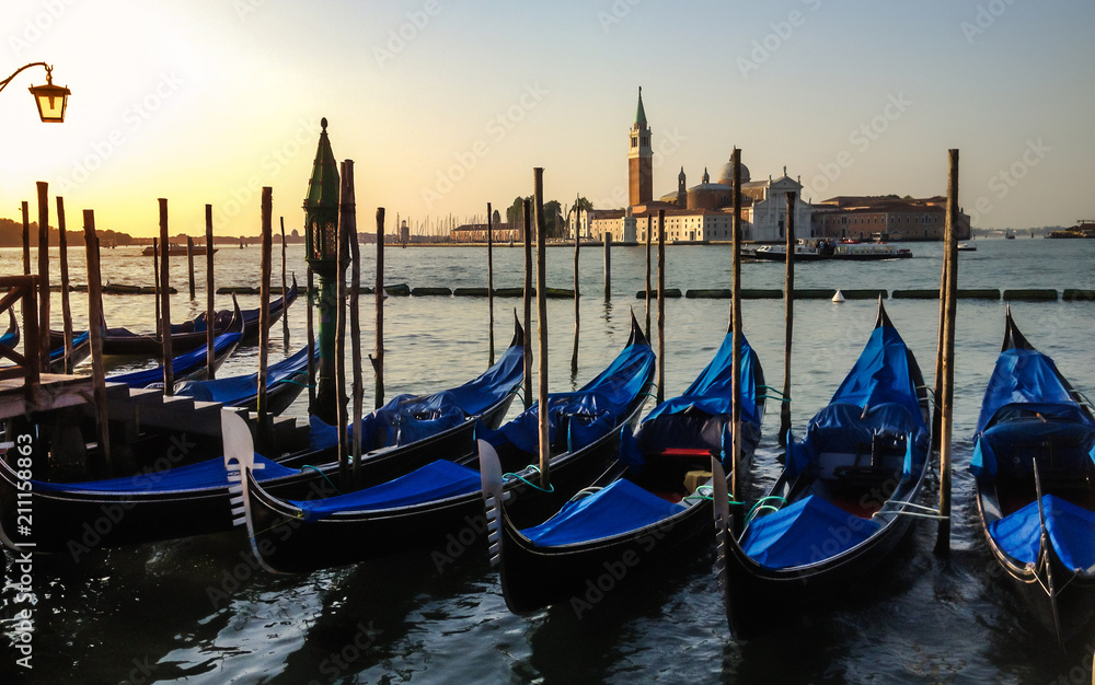 Gondolas anchored at pier of San Marco square at sunrise on Grand Canal towards San Giorgio Maggiore, Venice, Italy.