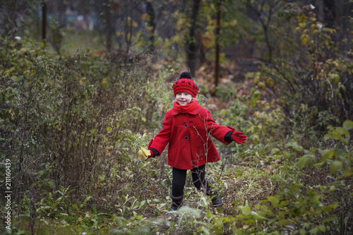 Little girl in a red coat at autumn