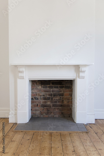 Victoriran wooden fireplace surround with white walls and wooden floor photo