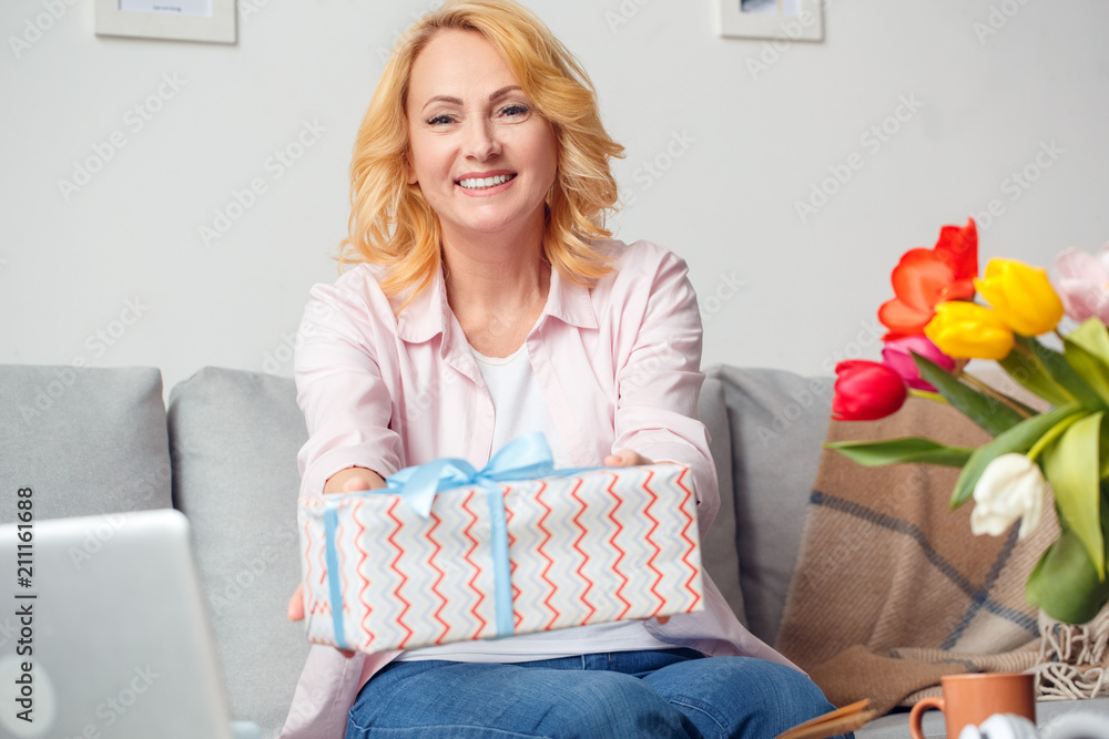 Senior woman at home celebration sitting giving present to camera cheerful Senior woman at home celebration sitting giving present to camera cheerful