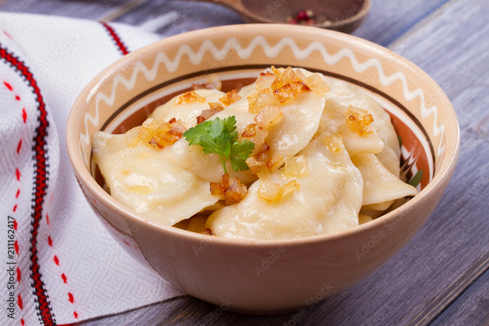Dumplings, filled with mashed potato - vegetarian dish. Varenyky, vareniki, pierogi, pyrohy in a bowl on wooden table. horizontal Dumplings, filled with mashed potato - vegetarian dish. Varenyky, vareniki, pierogi, pyrohy in a bowl on wooden table. horizontal