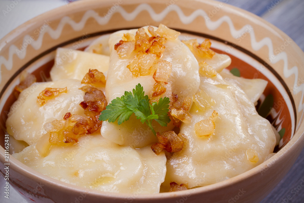 Dumplings, filled with mashed potato - vegetarian dish. Varenyky, vareniki, pierogi, pyrohy in a bowl on wooden table. horizontal Dumplings, filled with mashed potato - vegetarian dish. Varenyky, vareniki, pierogi, pyrohy in a bowl on wooden table. horizontal
