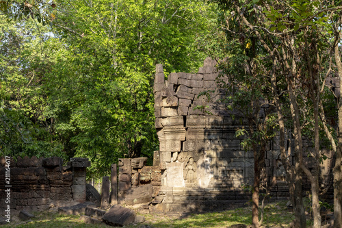 Ancient stone ruin in Angkor Wat temple. Carved stone wall in green forest. Khmer heritage temple ruin in jungle.