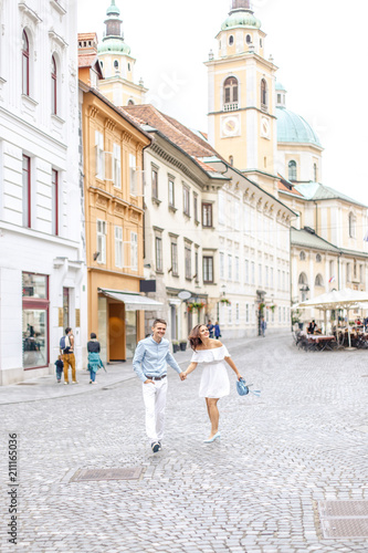 young beautiful couple, girl in white dress and man in blue shirt walking along the street © Alexander