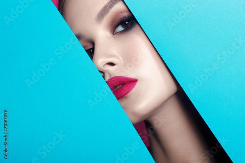 Young beautiful woman with clean perfect skin through gap in cardboard