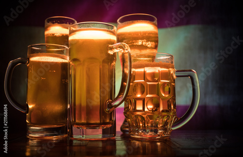 Creative concept. Beer glasses on table at dark toned foggy background with blurred view of flag of Spain. Support your country with beer concept