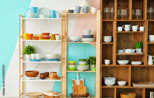 Different clean dishes on wooden shelves © Africa Studio