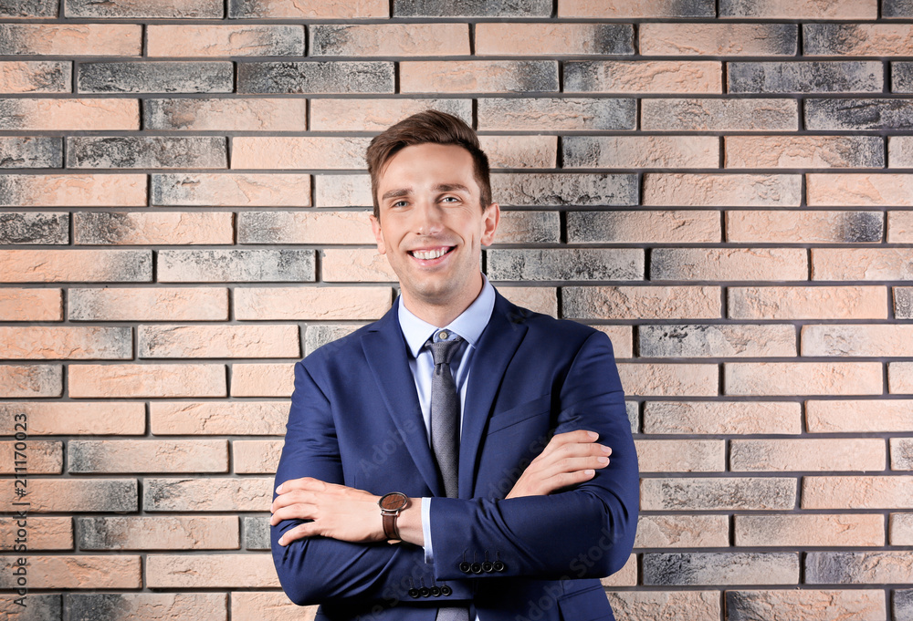 Handsome young man in suit near brick wall background Handsome young man in suit near brick wall background
