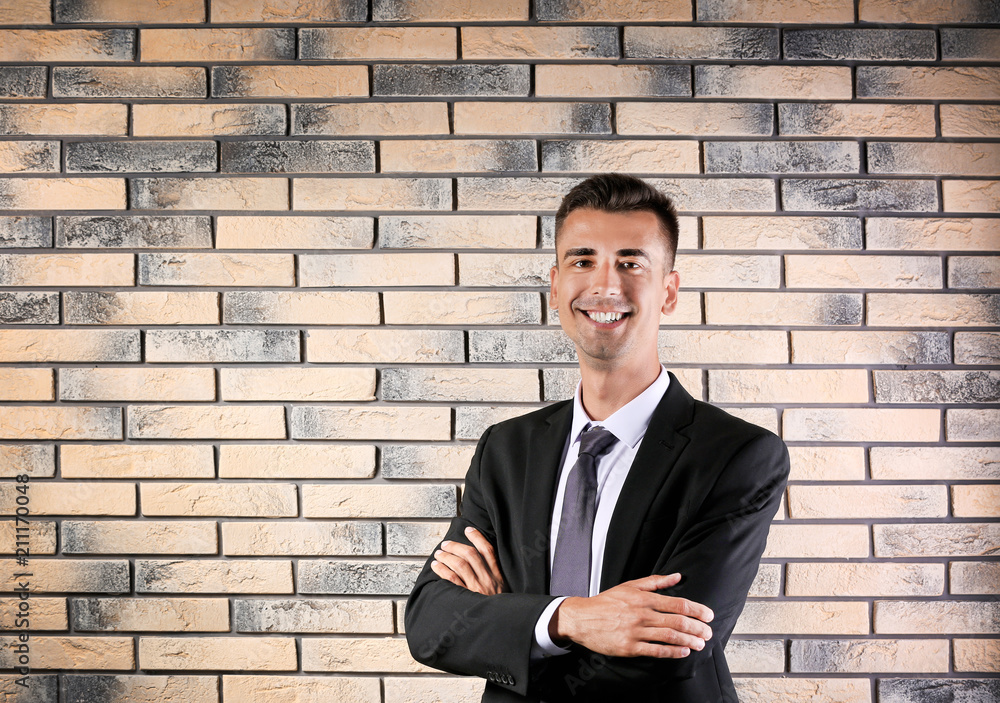 Handsome young man in suit near brick wall background Handsome young man in suit near brick wall background