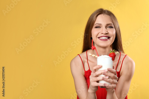 Young woman with glass of delicious milk shake on color background