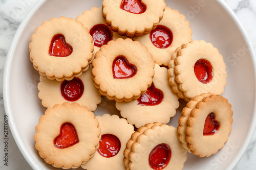 Traditional Christmas Linzer cookies with sweet jam on plate, top view