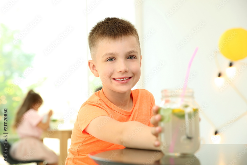 Little boy with natural lemonade at table indoors Little boy with natural lemonade at table indoors