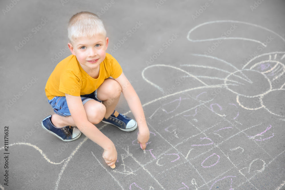 Naklejka premium Little child drawing bunny with colorful chalk on asphalt