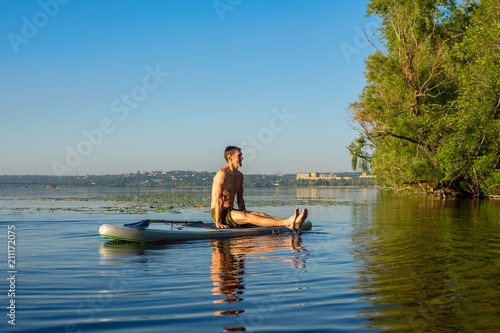 Man practicing yoga on a SUP board during sunrise