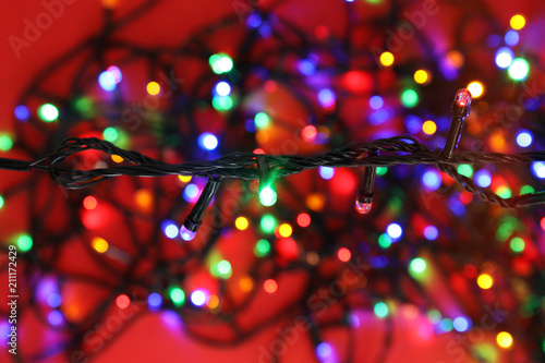 Glowing Christmas lights on color background, closeup
