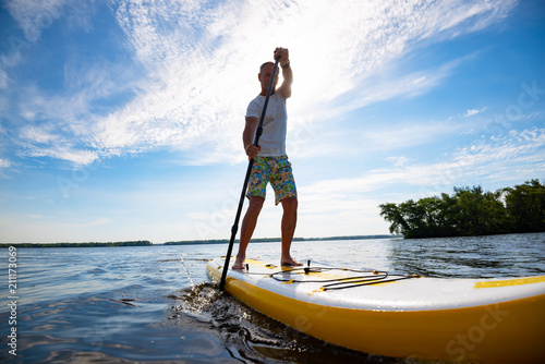 Joyful man sails on a SUP board in large river