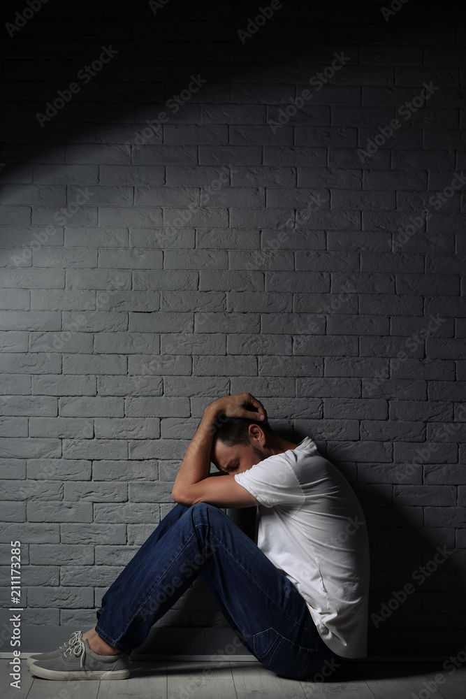 Lonely man suffering from depression near brick wall Lonely man suffering from depression near brick wall