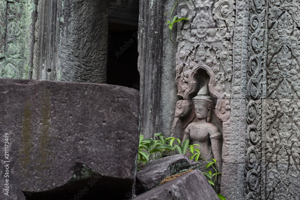 Ancient stone ruin in Angkor Wat temple. Stone carved human figure and floral. Khmer heritage temple ruin in jungle