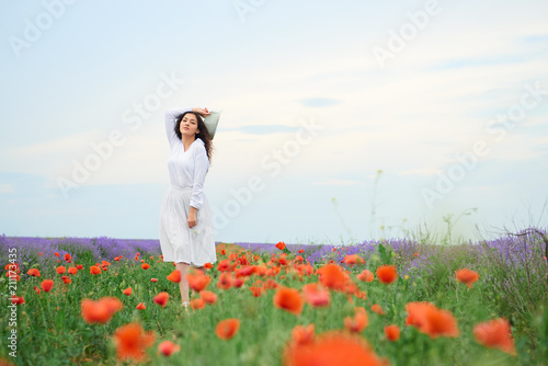 Fototapeta Naklejka Na Ścianę i Meble -  young girl is in the lavender field with red poppy flowers, beautiful summer landscape