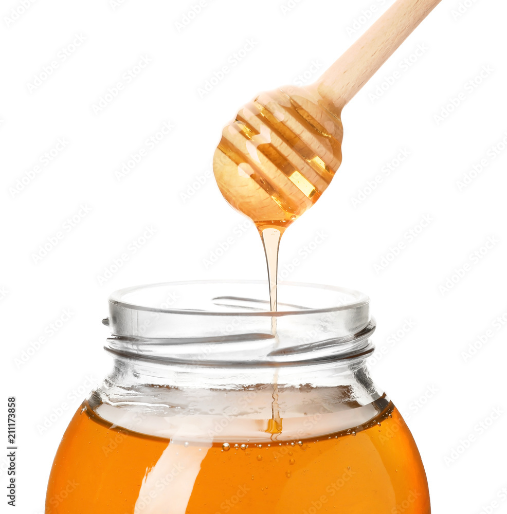 Honey dripping from dipper into jar on white background Honey dripping from dipper into jar on white background