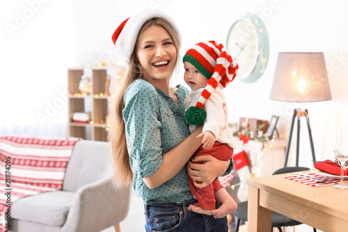 Young woman with baby in Christmas hats at home photo