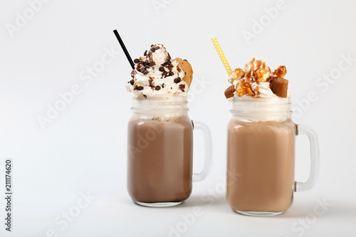 Mason jars with delicious milk shakes on white background