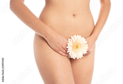 Young woman with flower showing smooth skin after bikini epilation on white background