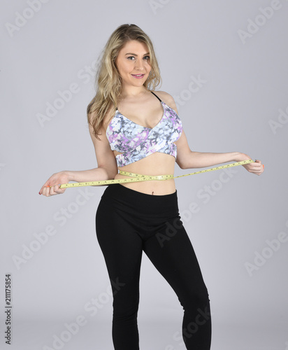 Beautiful young woman meaasuring her waistline photo