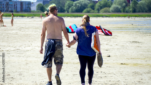 young couple. sporty European guy and fat girl are walking along the beach, holding each other's hands. The concept of love and understanding