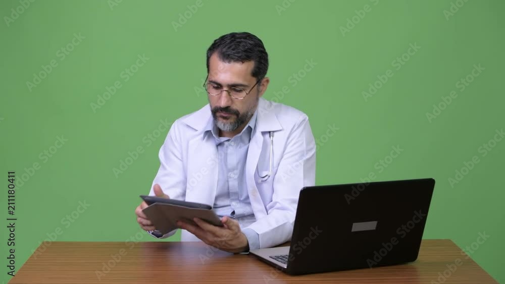 Handsome Persian bearded man doctor multi-tasking at work Handsome Persian bearded man doctor multi-tasking at work