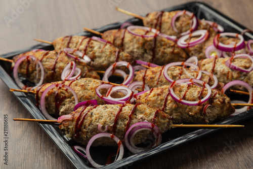 Lulya-kebab. Shish kebab on a stick, minced meat. Traditional Caucasian dish. On a cutting board, with green salad, ketchup, spices