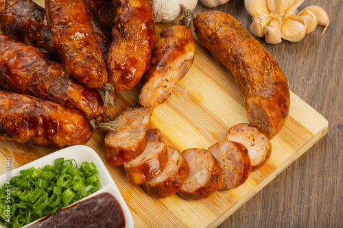 Homemade sausage on a wooden background with seasonings and sauce.