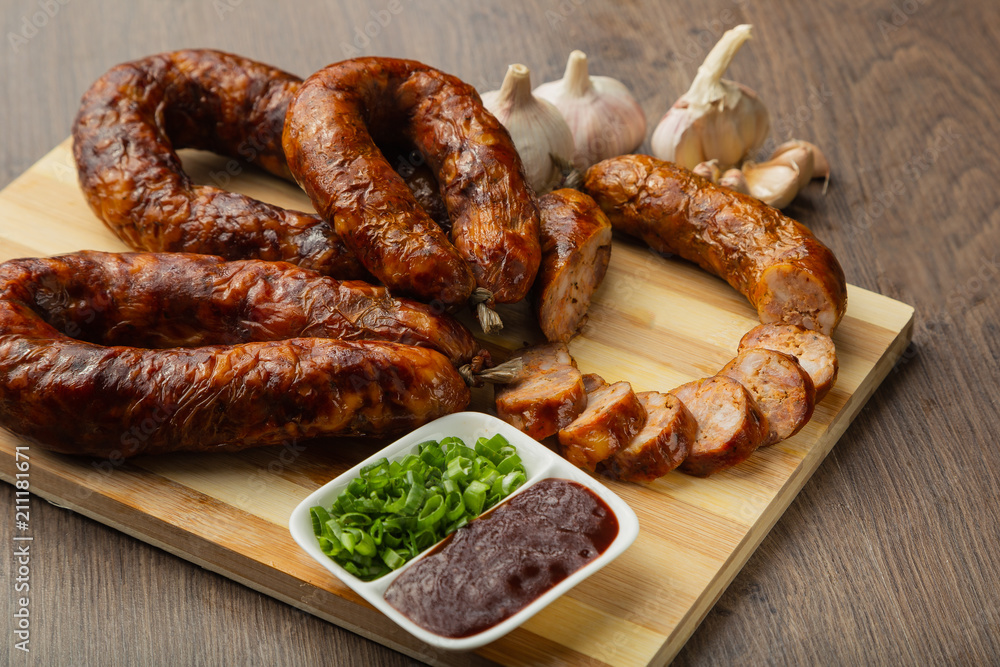 Homemade sausage on a wooden background with seasonings and sauce. Homemade sausage on a wooden background with seasonings and sauce.