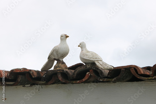 duas pombas de cerâmica no telhado photo