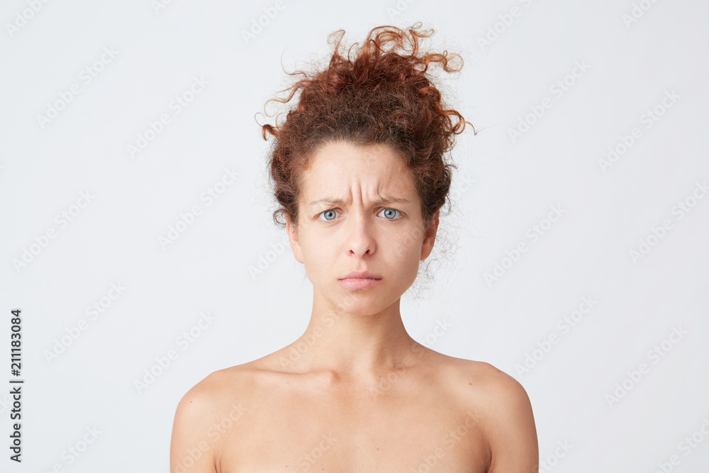 Close up shot of sad unhappy beautiful young woman with curly hair and perfect fresh clean skin worried about her future career isolated over white background Stands half naked indoor Close up shot of sad unhappy beautiful young woman with curly hair and perfect fresh clean skin worried about her future career isolated over white background Stands half naked indoor