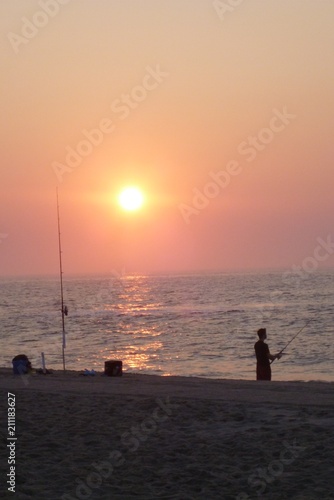 Sunrise over ocean beach waves Fisherman