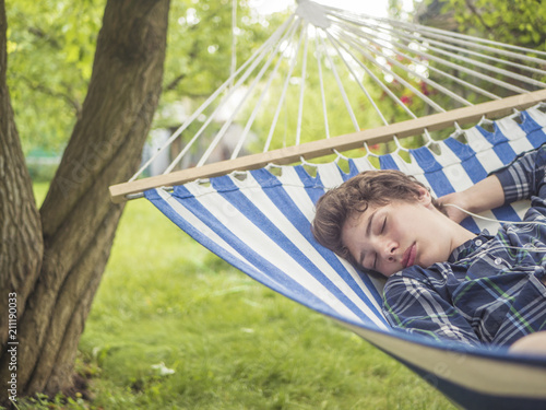 Fotografie young male teenager sleeping on the hammock in garden on a summer day