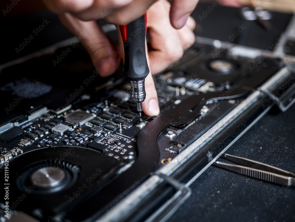 hand holding tweezers and screwdriver repairing the laptop close up computer fixing concept hand holding tweezers and screwdriver repairing the laptop close up computer fixing concept