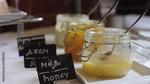 honey, jam and condensed milk in jars on the served table in buffet in the new hotel