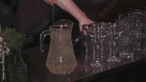 The barman prepares homemade lemonade, stirs with a spoon in a jug