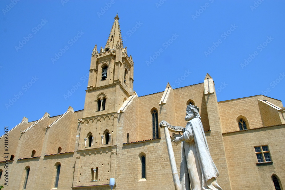 Fototapeta premium Ville de Salon-de-Provence, Collégiale Saint-Laurent (abrite le tombeau de Nostradamus) et statue représentant un personnage jouant de la harpe, département des Bouches-du-Rhône, France