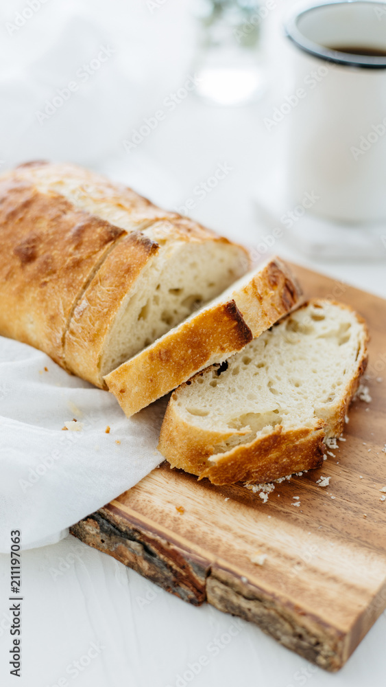 Loaf of bread sliced on wood cutting board and white linen. Loaf of bread sliced on wood cutting board and white linen.